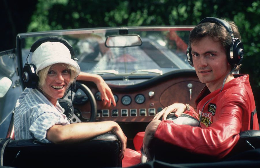 Countess Gunilla Bismarck listening to car radio with headphones in a sports car