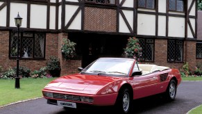 Red Ferrari Mondial Cabriolet parked in front of a house, this is the cheapest Ferrari one can currently buy