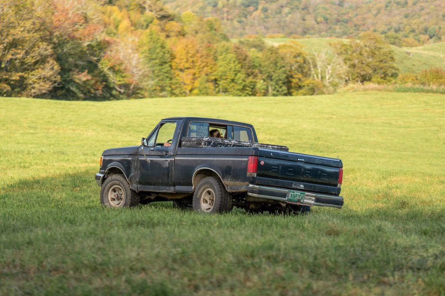 Black pickup truck driving through a field.