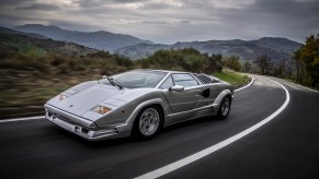 A silver 1989 Lamborghini Countach 25th Anniversary Edition driving around a mountain road