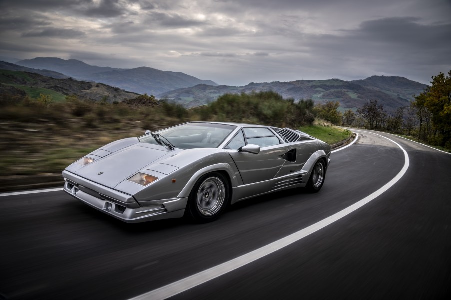 A silver 1989 Lamborghini Countach 25th Anniversary Edition driving around a mountain road