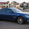 A blue 2014 BMW Alpina B7 with tinted windows by a marina