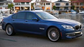 A blue 2014 BMW Alpina B7 with tinted windows by a marina