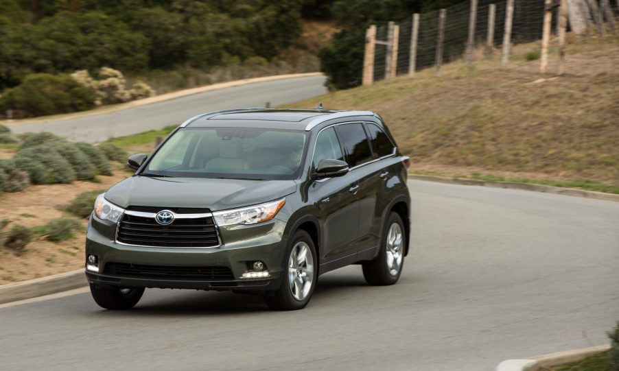 A gray 2014 Toyota Highlander driving down a winding road.