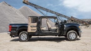 Black Ford Super Duty pickup truck parked on a jobsite with all four of its supercab doors open.