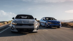 a grey kia k5 gt line and kia k5 gt drive along a road showing off the sleek and modern styling