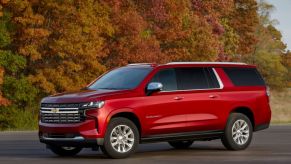 A red 2022 Chevrolet Suburban parked outdoors in front of a wooded area.