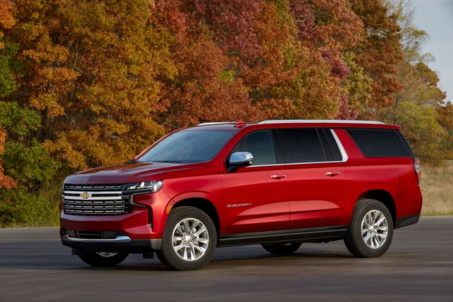 A red 2022 Chevrolet Suburban parked outdoors in front of a wooded area.