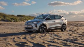 A silver gray 2022 Chevy Bolt EUV electric vehicle (EV) compact SUV parked on a sandy beach