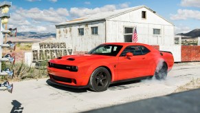 a red 2022 dodge challenger shows off its supercharged power with an aggressive burnout