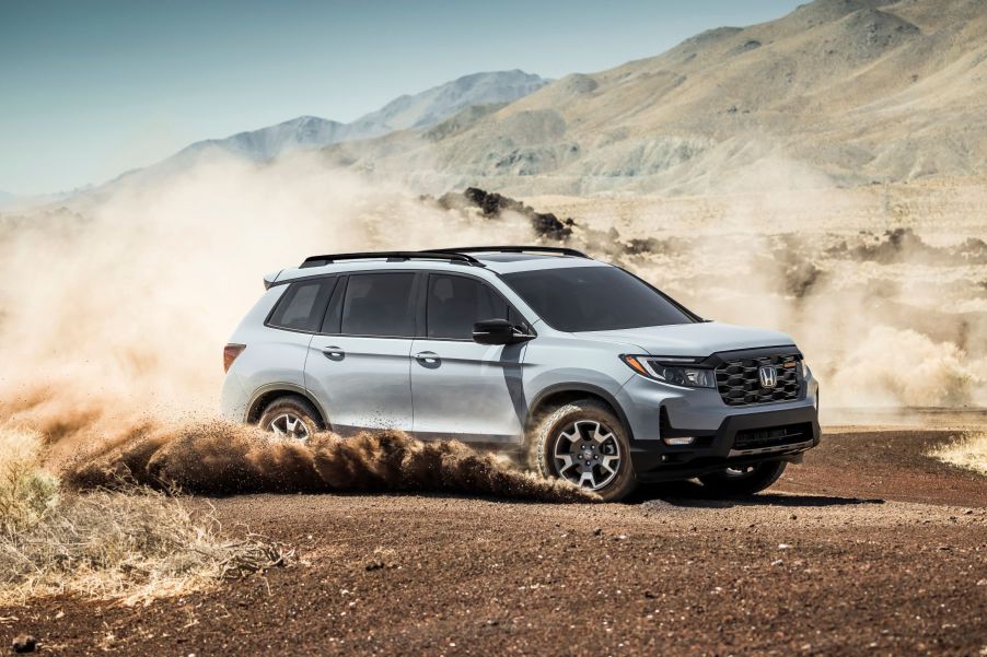 2022 Honda Passport Trailsport compact adventure SUV dirting through a dirt field and kicking up dust clouds