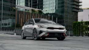 A gray 2022 Kia Forte GT compact sedan model parked in front of a towering glass skyscraper