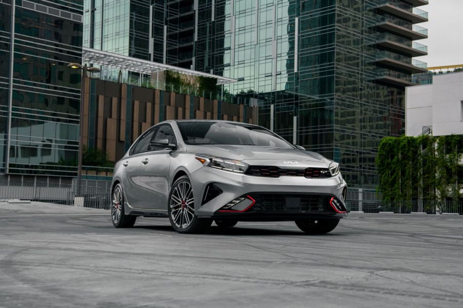 A gray 2022 Kia Forte GT compact sedan model parked in front of a towering glass skyscraper