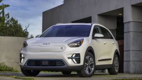 A white 2022 Kia Niro EV electric compact SUV model parked outside of a concrete garage