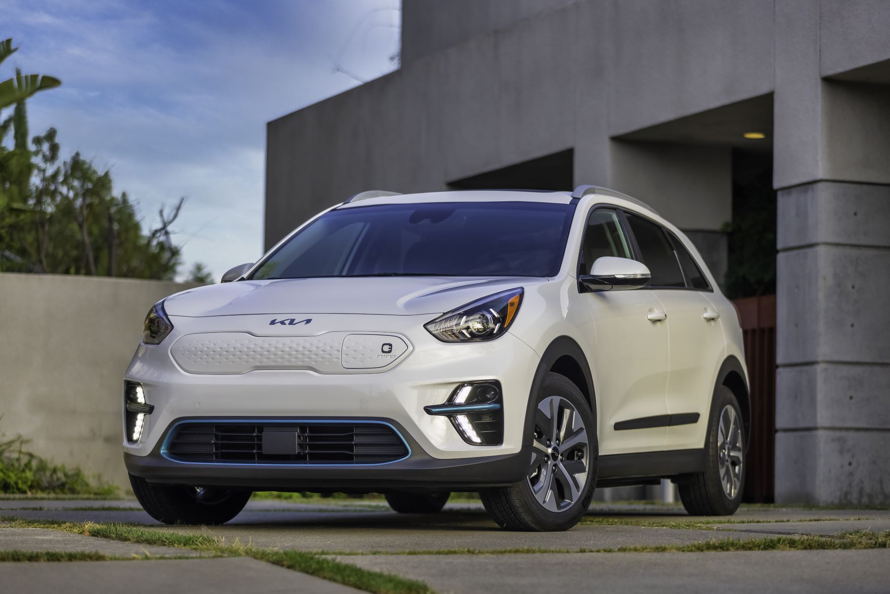 A white 2022 Kia Niro EV electric compact SUV model parked outside of a concrete garage