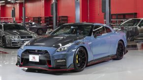 A blue-and-carbon-fiber 2022 Nissan GT-R NISMO Special Edition in a garage in front of classic Skyline GT-Rs