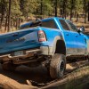 Blue Ram 1500 TRX off-roading in front of a wooded mountainside.