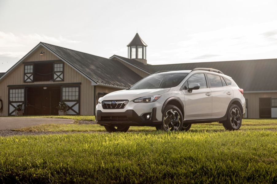 A white 2022 Subaru Crosstrek in a green field with a barn behind it that is a part of the car sales industry.