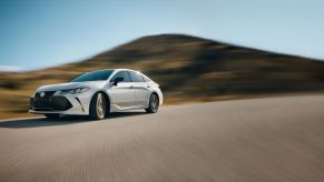 White 2022 Toyota Avalon, the best-in-class full-size sedan, drifting around a corner on pavement