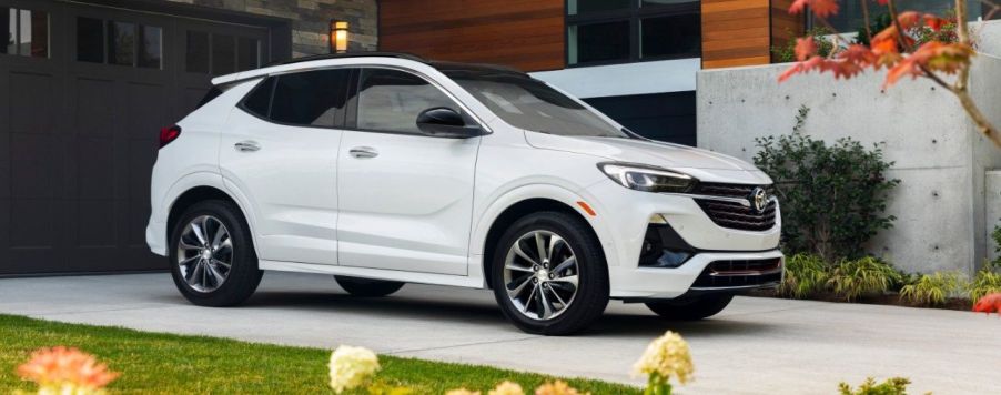 A white 2023 Buick Encore GX subcompact crossover SUV model parked on a driveway near flowerbeds