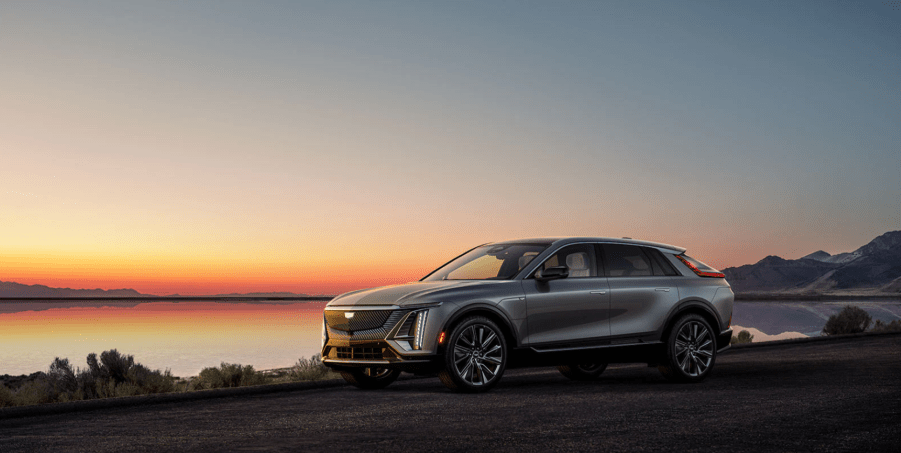 A gray 2023 Cadillac Lyriq luxury electric SUV model parked near a beach during sunset