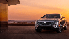 A gray 2023 Cadillac Lyriq luxury electric SUV model parked outside of a luxury house during a sunset sky