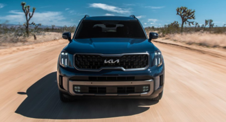 A green 2023 Kia Telluride is driving off-road.