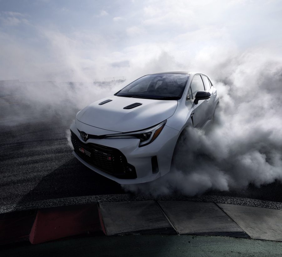 The front 3/4 view of a white 2023 Toyota GR Corolla Circuit Edition doing a burnout on a track