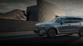 A blue 2023 BMW X7 against a shadlowy background.