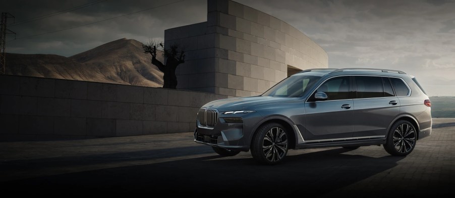 A blue 2023 BMW X7 against a shadlowy background.