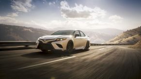 White Toyota TRD driving along a mountain road; the 2023 Camry midsize sedan will include a TRD variant