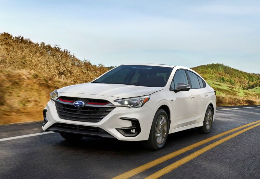 2023 Subaru Legacy Sport sedan in white, driving along a paved road in spring