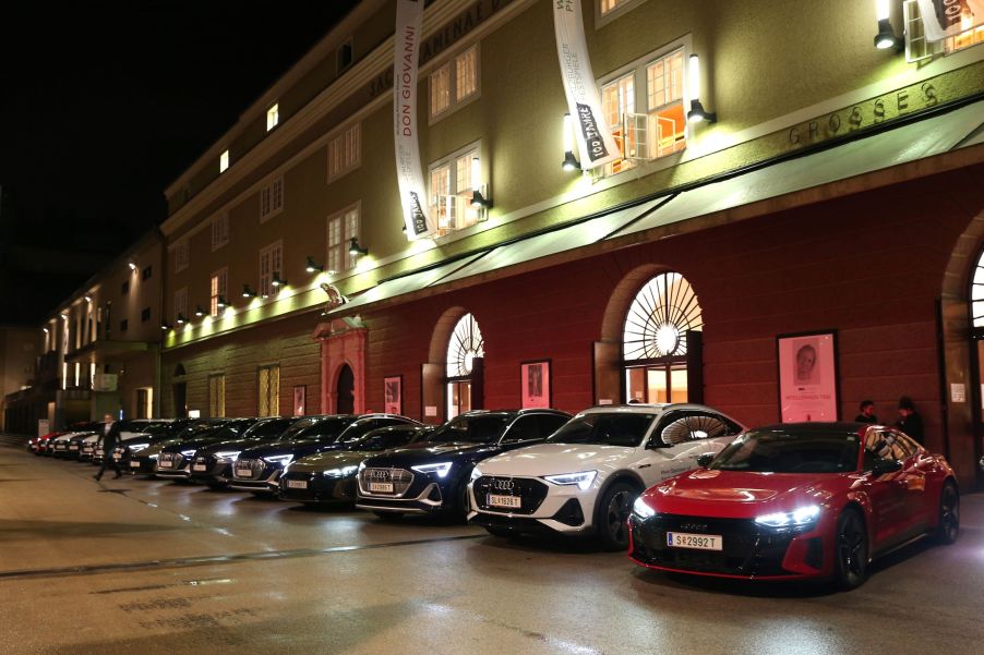 A row of Audi cars, potentially electric Audi vehicles, in a row in front of a well lit building.