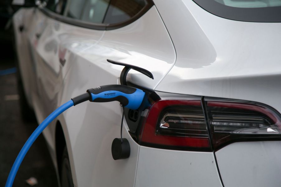 A white EV plugged into a charger.