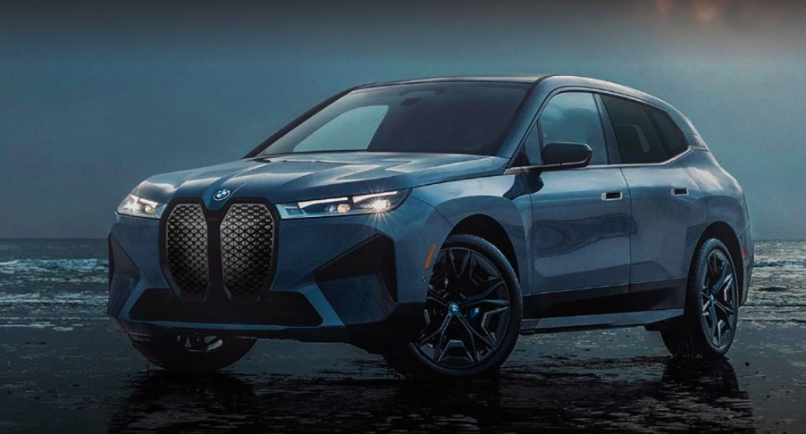 A blue 2022 BMW iX electric luxury SUV is parked with water in the background.