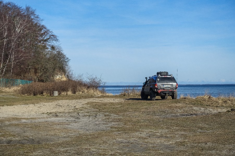 A Jeep Grand Cherokee WJ sits on a beachfront.