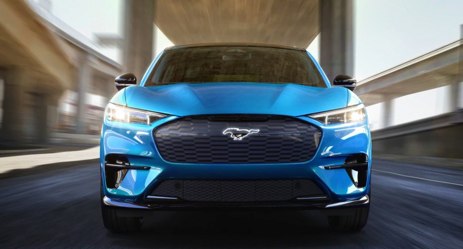 A blue 2022 Ford Mustang Mach-E electric SUV is driving on the road.