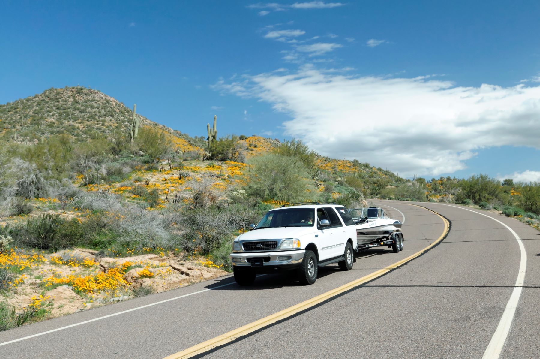 A Ford SUV towing a boat on North Lake Road at the Bartlett Lake Recreation Area in Tonto National Forest of Arizona