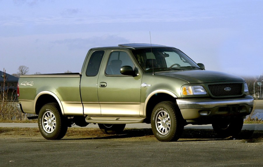 A Ford F-150 with green paint sits on a paved road.