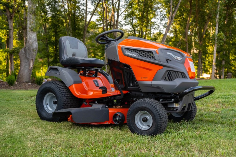 Lawn mowing tractor parked in front of a row of trees.