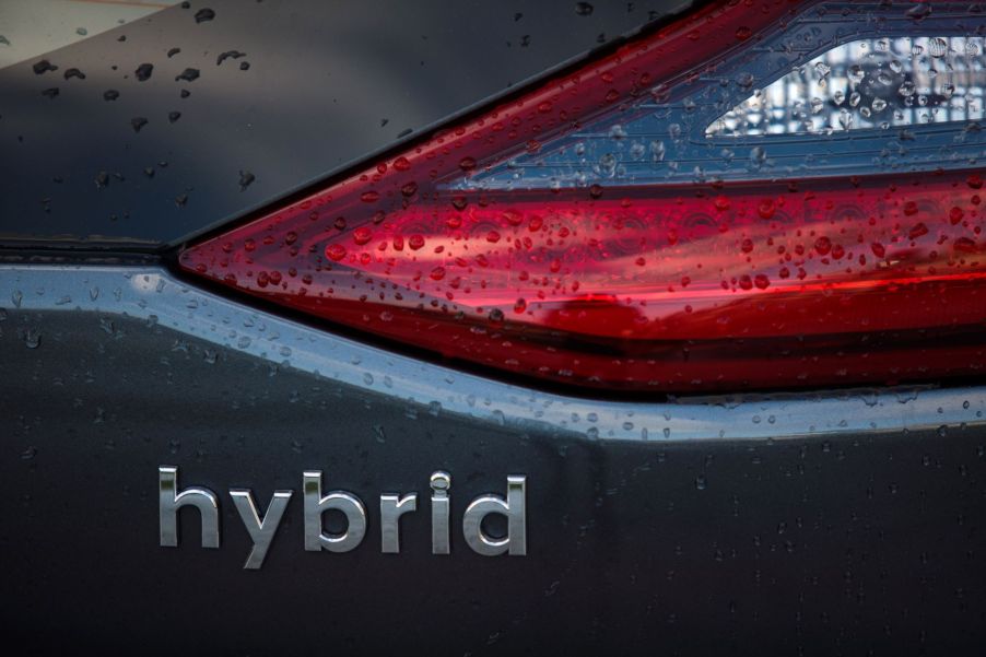 Hybrid written on the back of a gray car.