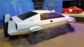 The white James Bond submarine car, used as inspiration for the Tesla Cybertruck, in front of a blue display indoors.