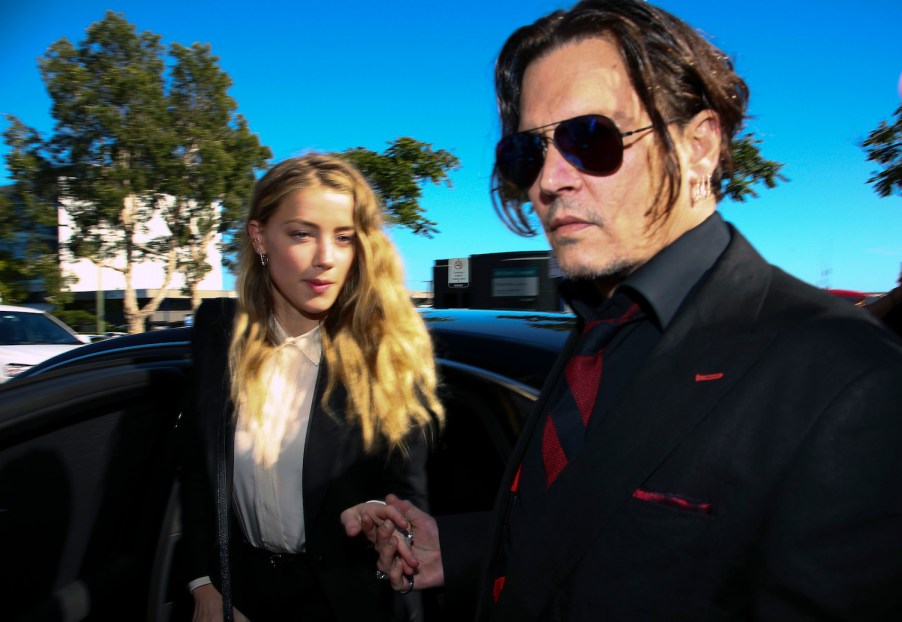 Johnny Depp and Amber Heard getting out of a black sedan in a sunny parking lot.