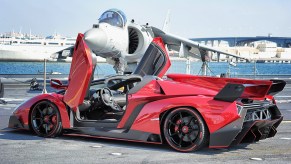 Red Lamborghini Veneno Roadster, the most expensive Lamborghini ever built, sitting in front of a fighter jet