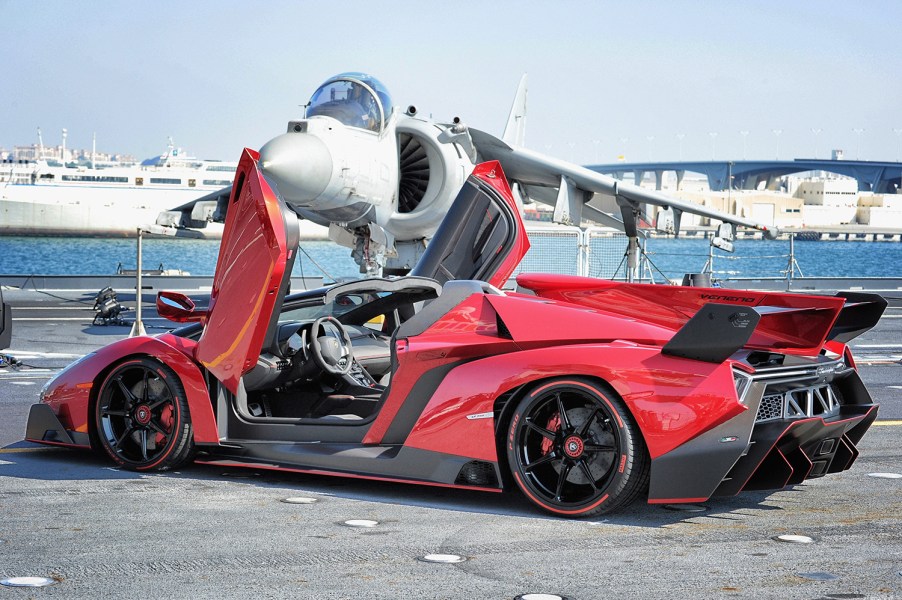 Red Lamborghini Veneno Roadster, the most expensive Lamborghini ever built, sitting in front of a fighter jet