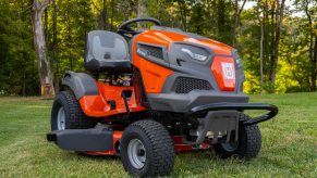 Lawn mowing tractor parked in front of a row of trees.