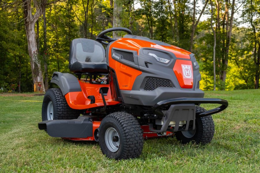 Lawn mowing tractor parked in front of a row of trees.