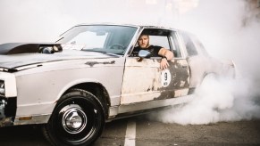 Man driving an old car with smoke coming out of it, highlighting bad car smells and how to remove them