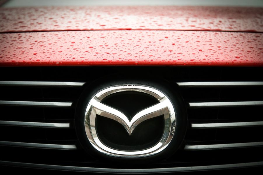 A silver Mazda logo, creator of the Mazda museum, on a red background.