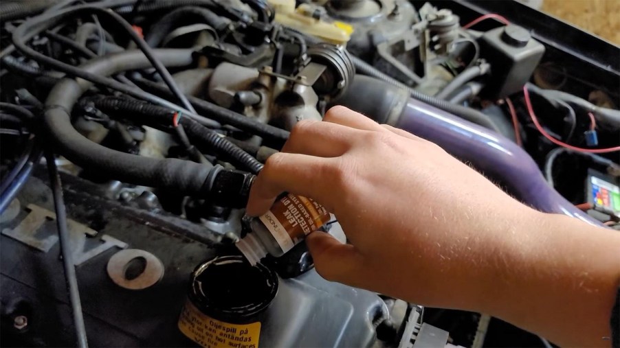 Braden Carlson of Motorbiscuit pouring UV leak detecting oil dye into his Volvo 740 SE station wagon